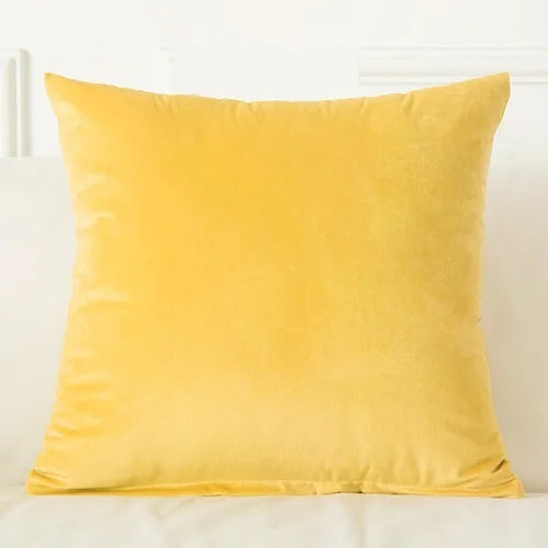 A square, solid yellow velvet decorative cushion cover resting on a white surface.