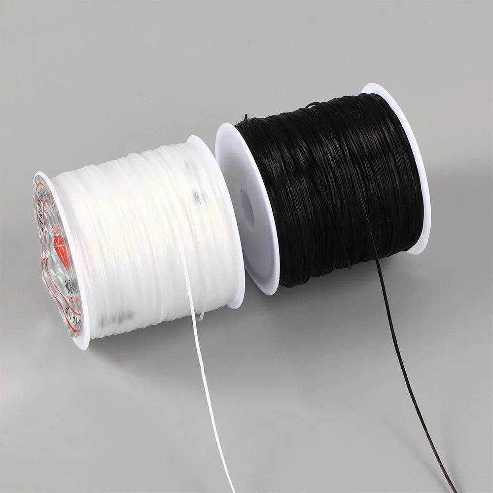 A spool of black flat elastic beading thread next to a spool of white flat elastic beading thread.