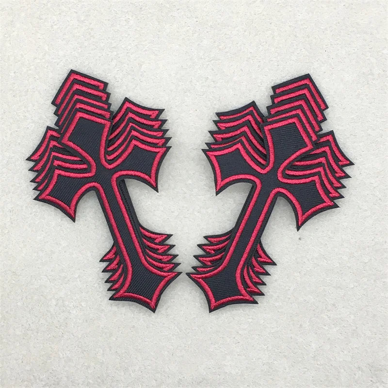 Two black and pink embroidered cross applique patches on a light gray background