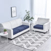 A white sofa and armchair set with dark blue seat cushion covers placed on a rug in a bright room.