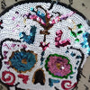 A white skull design made of sequins and embroidery featuring colorful floral elements.