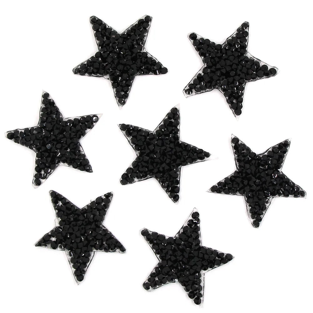A collection of black glitter rhinestone iron-on star patches for clothing.
