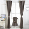 Two gray fabric curtains with magnetic pearl ball tiebacks hanging in a window.