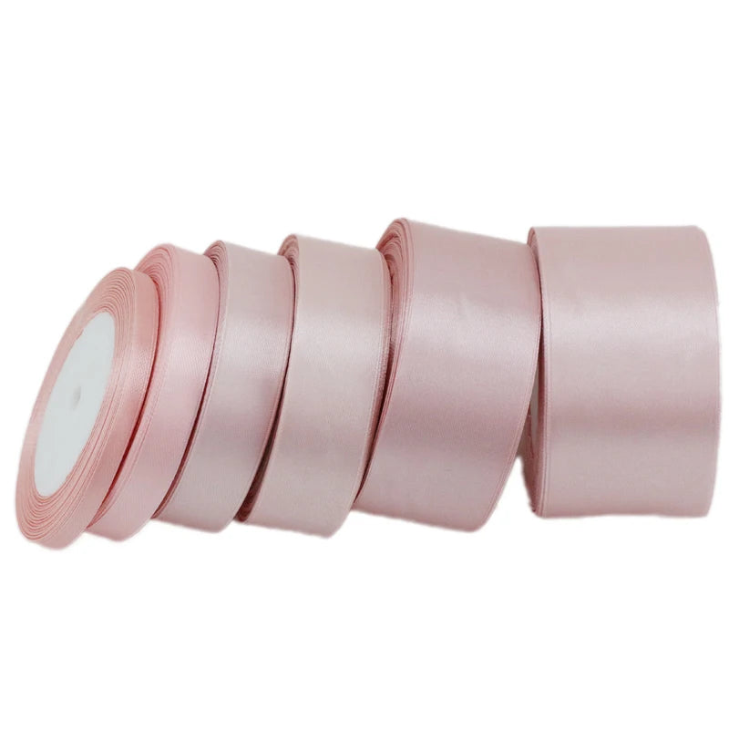 A roll of light pink satin gift ribbon, showing several individual rolls stacked horizontally.