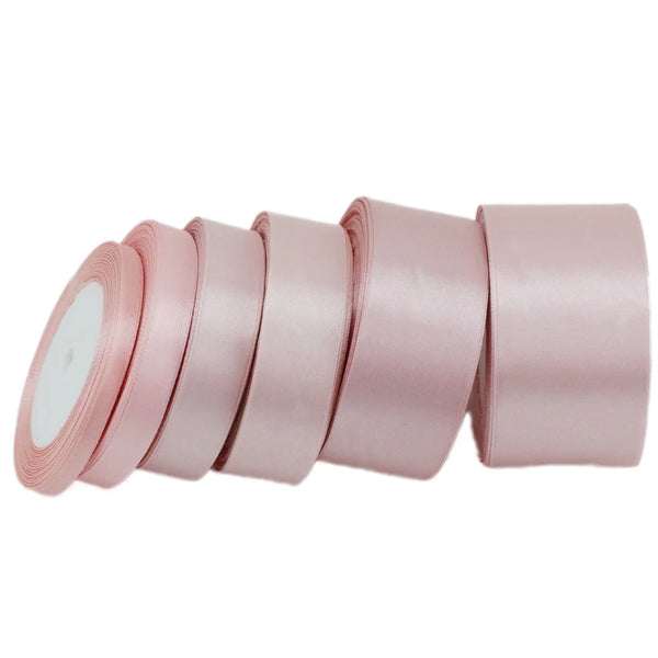 A roll of light pink satin gift ribbon, showing several individual rolls stacked horizontally.