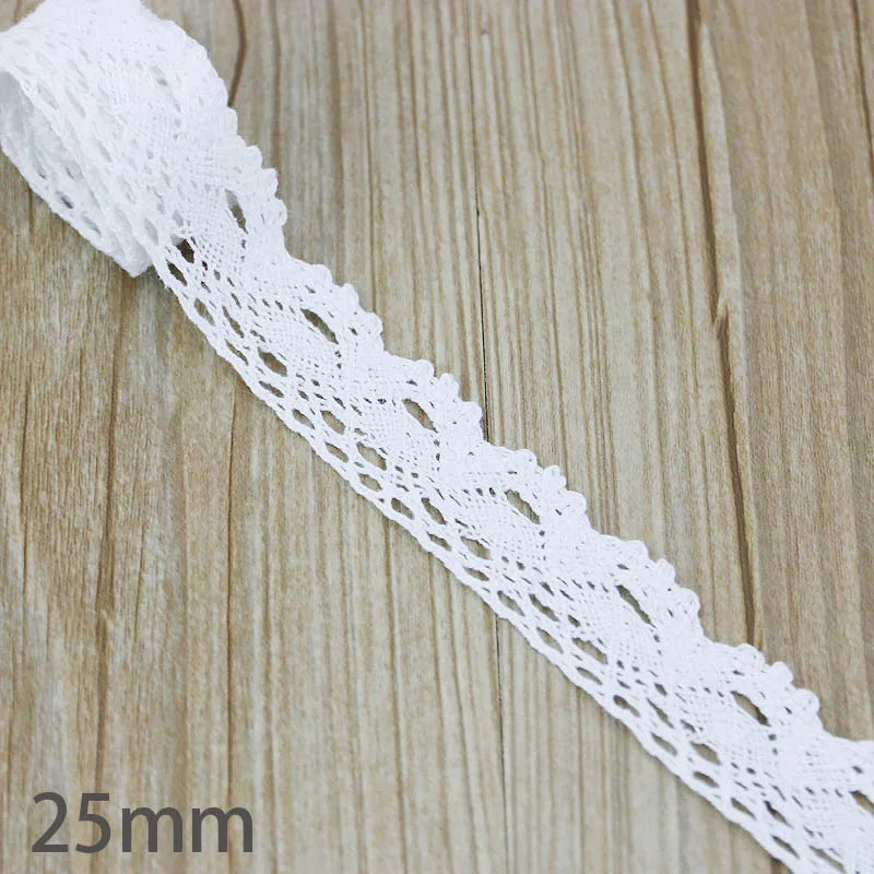 White cotton embroidered lace trim shown on a wooden surface.