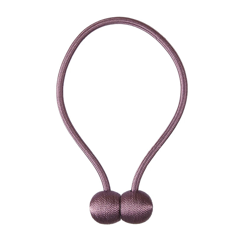 A pair of mauve magnetic pearl ball curtain tiebacks with a thin cord.