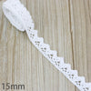 A close-up of white cotton embroidered lace trim with a delicate eyelet pattern on a wooden surface.