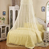 Elegant round mosquito net canopy with sheer white fabric draped over a light yellow bed.