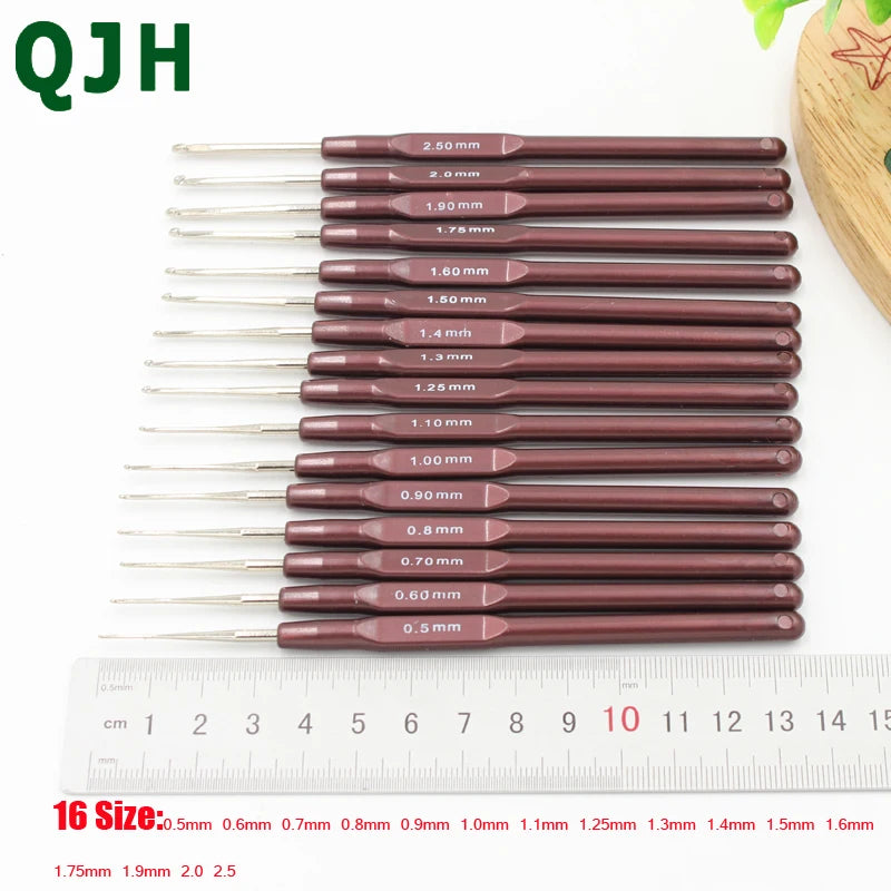 A set of sixteen crochet hooks with various sizes ranging from 0.5 mm to 2.5 mm displayed next to a ruler.