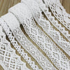 Roll of white cotton embroidered lace trim featuring intricate eyelet patterns