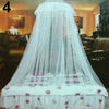 A white mosquito net canopy draped over a bed, featuring pink floral accents.