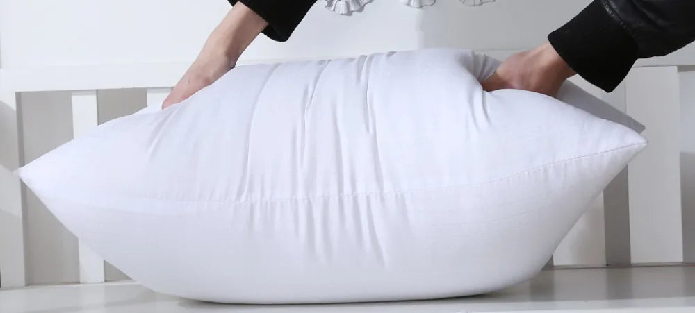 A white extra-long body pillow being held by hands, demonstrating its full-body support.