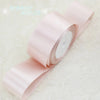 A roll of light pink satin gift ribbon, showing the smooth texture and white core.