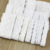 A roll of white cotton embroidered lace trim cut into strips on a wooden surface.