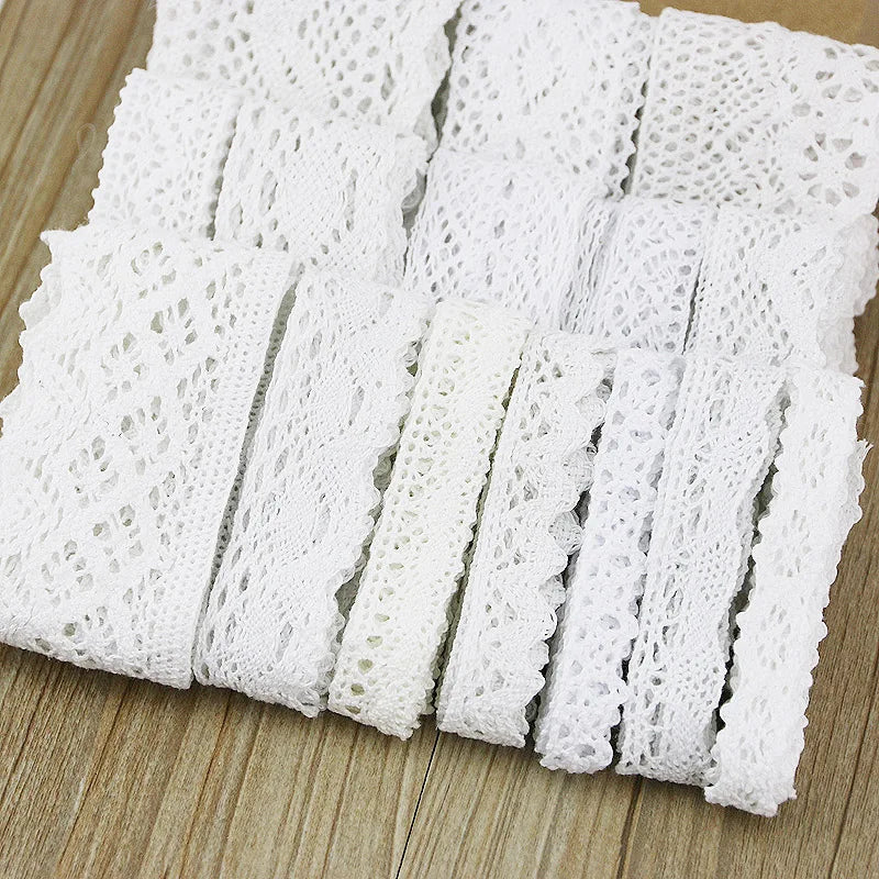 A roll of white cotton embroidered lace trim cut into strips on a wooden surface.