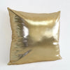 A square pillow covered in shiny, metallic gold fabric.