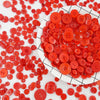 A pile of small, round, red wooden buttons scattered across a white surface.