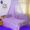 A bed draped with a purple mosquito net canopy in a bedroom setting.