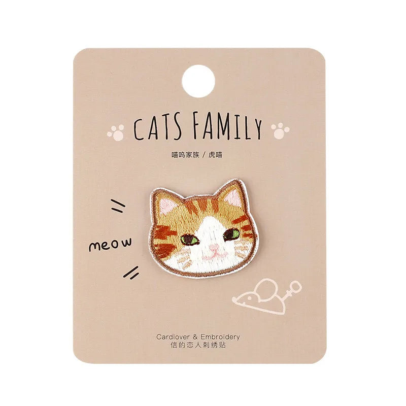 Handmade embroidered cat patch featuring a white and orange tabby face on a kraft paper tag.