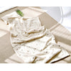 A soft cream coral fleece flannel blanket with small leaf patterns is draped on a light beige surface.