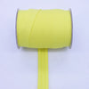 A roll of bright yellow durable bias tape binding ribbon with a vertical strip extending from the center.