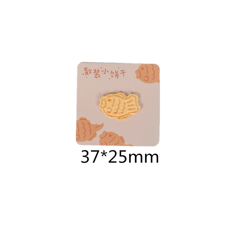 A square patch featuring an embroidered illustration of a fish on a light pink background.