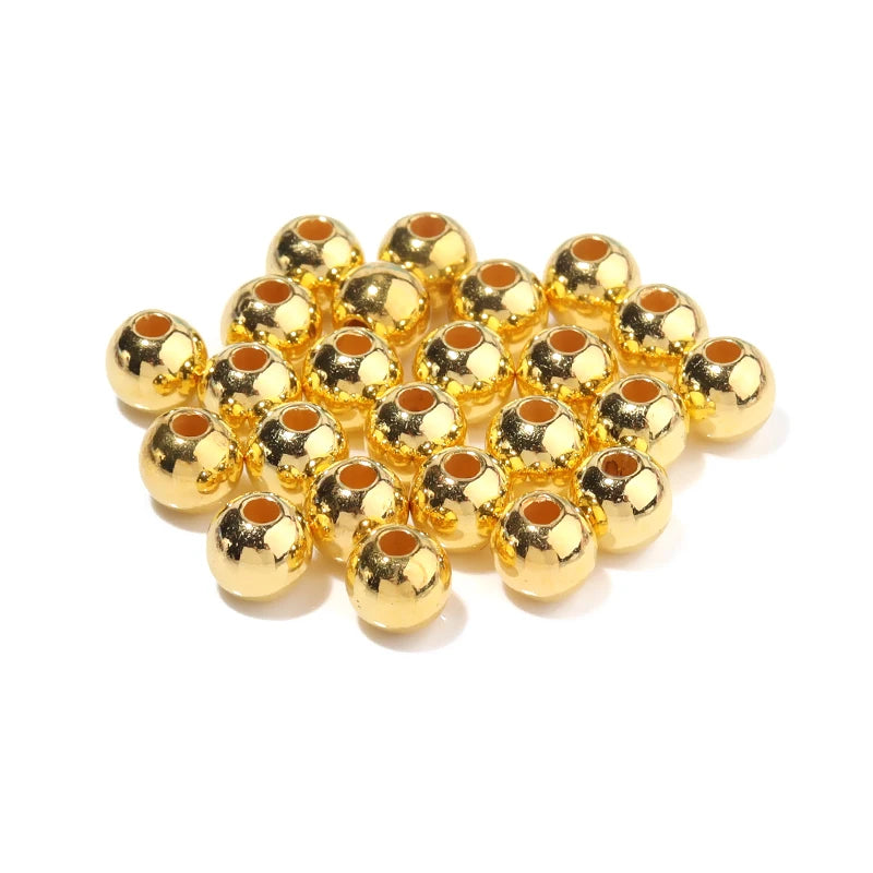 A pile of small, round imitation pearl beads in gold color for DIY jewelry making