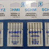 A collection of SCHMETZ universal sewing machine needles packaged in plastic trays.