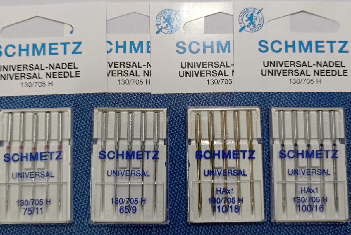 A collection of SCHMETZ universal sewing machine needles packaged in plastic trays.