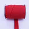 A roll of bright red durable bias tape binding ribbon with a pink edge and a red stick.