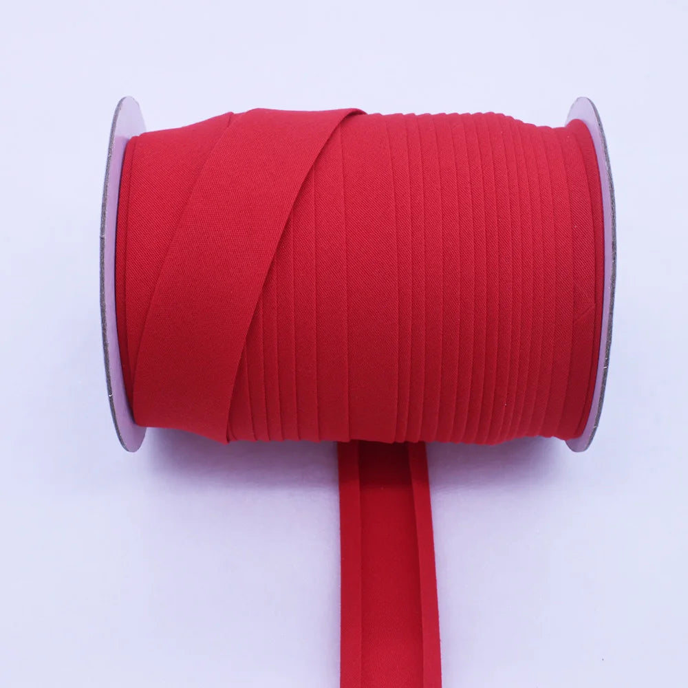 A roll of bright red durable bias tape binding ribbon with a pink edge and a red stick.