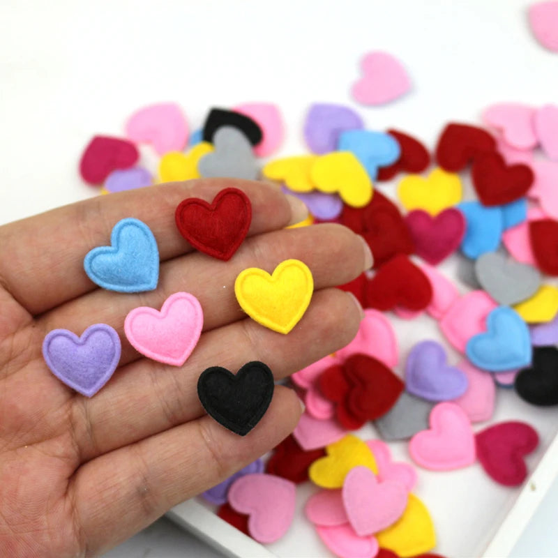 A hand holds various colorful felt heart appliques for crafting and decoration.