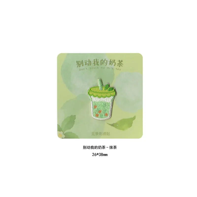 A green embroidered patch shaped like a cup of iced matcha tea with a straw.