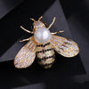 A gold-toned crystal bee brooch featuring a pearl accent and detailed wing design.