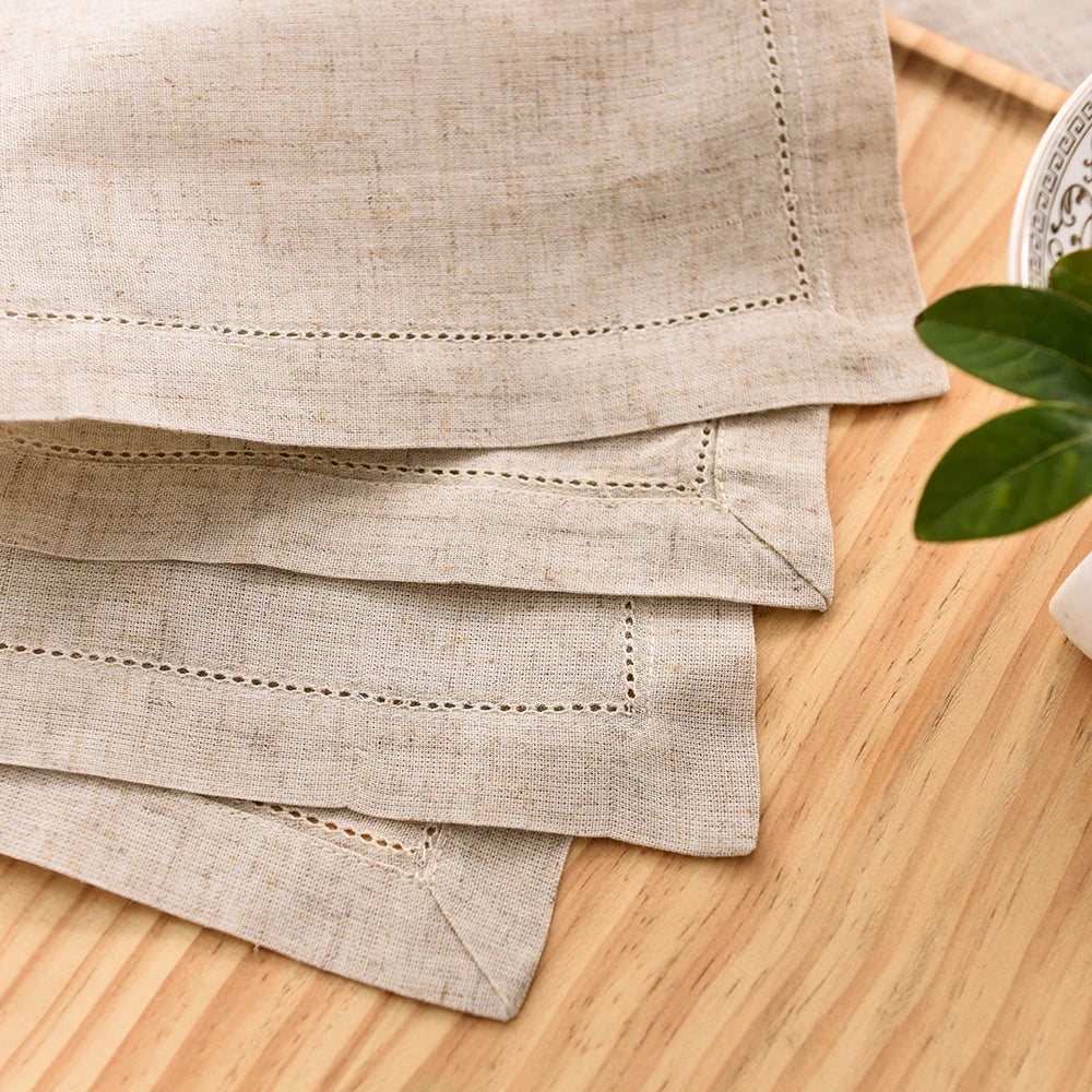 A stack of natural linen table linens and napkins in beige tones on a wooden surface.