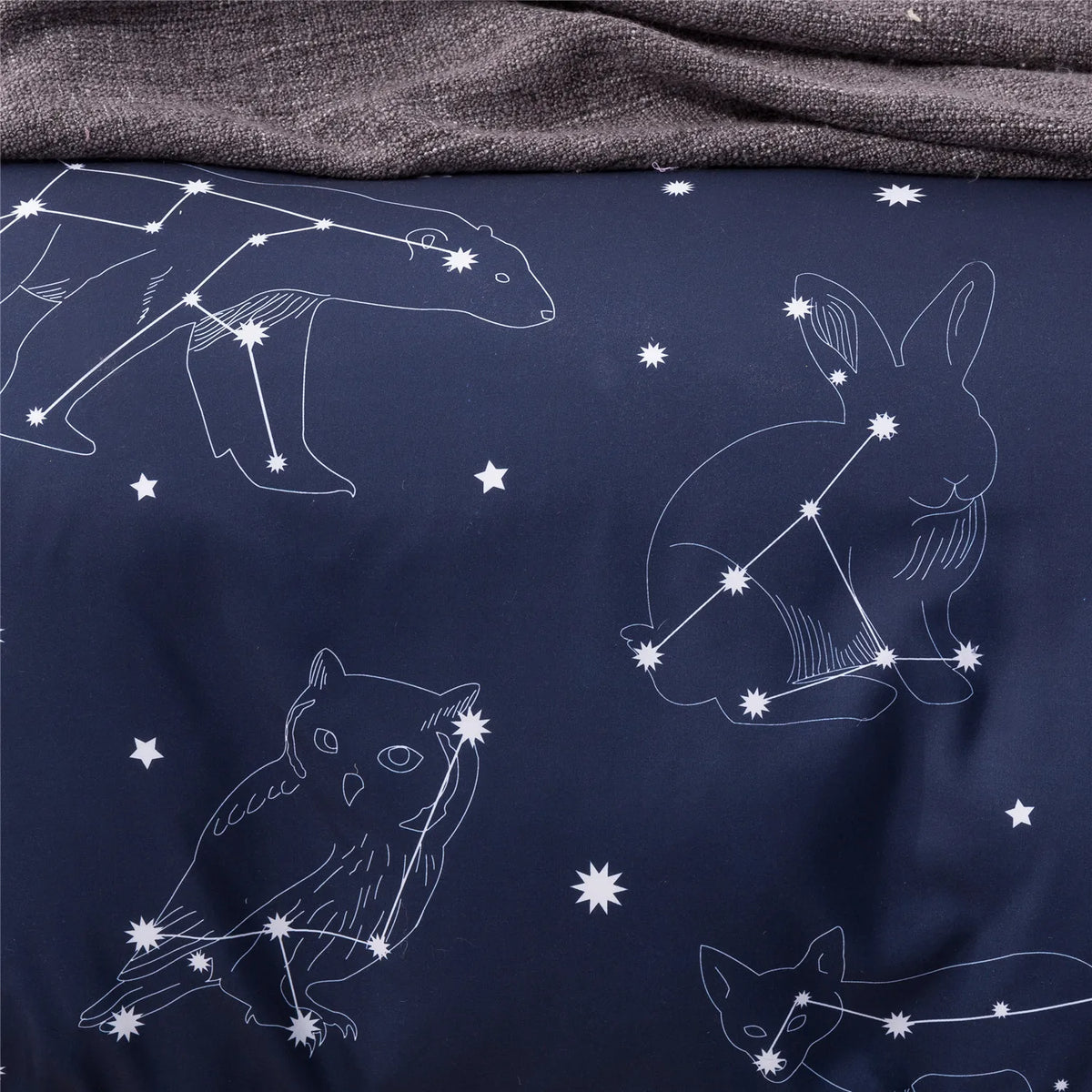 A dark blue duvet cover featuring white line art illustrations of woodland animals like a bear, rabbit, and owl against a sta