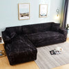 A dark brown patterned sofa protector cover displayed on a sofa with framed artwork in a bright room.