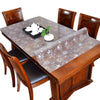 A wooden dining table set with chairs and a transparent PVC tablecloth.