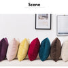 A row of solid velvet decorative cushion covers in various colors lined up on a white sofa.