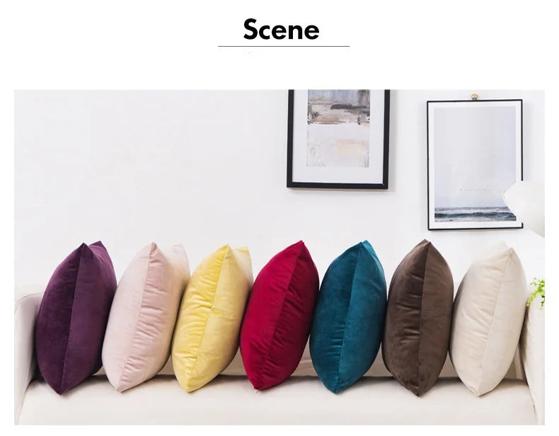 A row of solid velvet decorative cushion covers in various colors lined up on a white sofa.