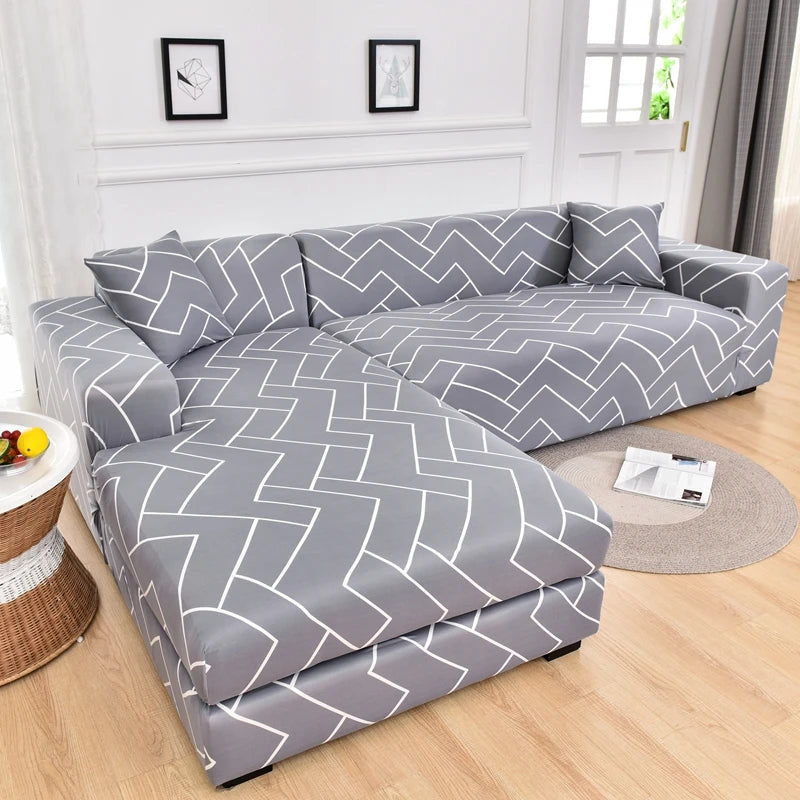 A gray L-shaped sofa protector cover featuring a geometric zigzag pattern placed on a light wood floor.