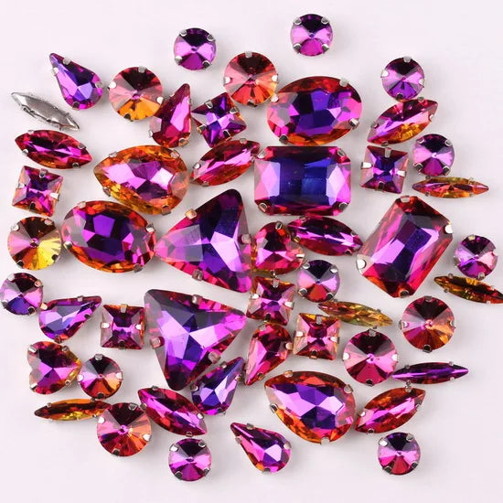 A collection of iridescent purple and pink rhinestones and silver claws used for decoration.
