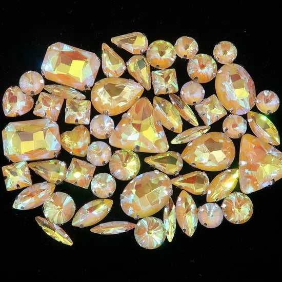A collection of 50 faceted, golden-yellow and orange silver claw rhinestones arranged on a dark background.