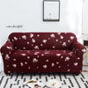 A deep burgundy stretch floral elastic sofa cover featuring pink and white flowers on a white rug.