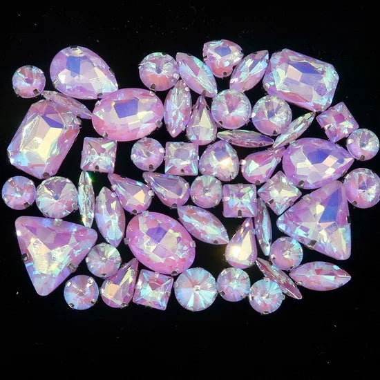 A collection of pink and purple faceted rhinestones and crystals arranged in a decorative pattern.