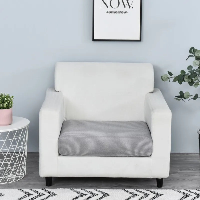 A white armchair with a gray seat cushion cover sits against a light blue wall.