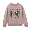 A light pink sweatshirt featuring a graphic print of the word SISTAS and five women.