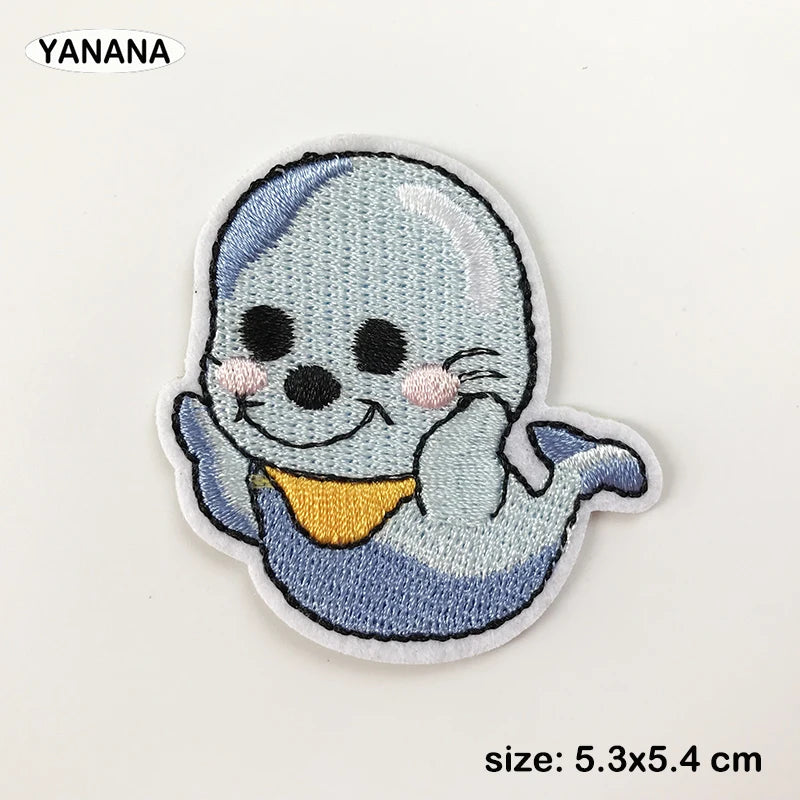 A light blue embroidered patch of a smiling, blob-like creature with pink accents.