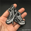 Pair of black embroidered punk style boots or shoes shown held in a hand